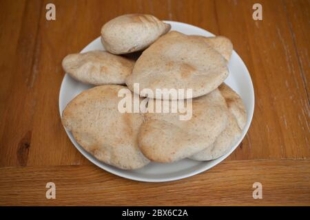 Half a dozen freshly baked flat pitta breads served on a white plate Stock Photo