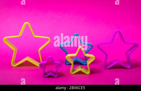 Plastic molds of blue and yellow colors for making cookies in the shape of a star on a pink background. Culinary or party concept. Flat lay with copys Stock Photo