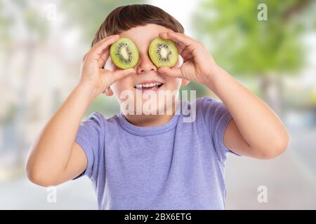 Little boy child with kiwi fruit having fun town happy happiness healthy eating outdoors Stock Photo