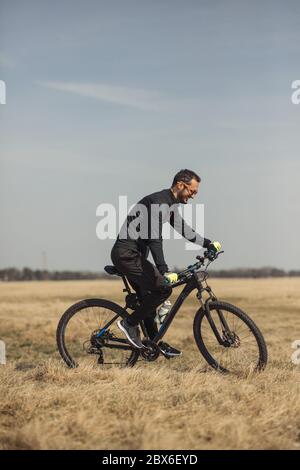 Young man riding a bike on grass field Stock Photo