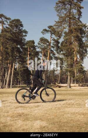 Young man riding a bike on grass field Stock Photo