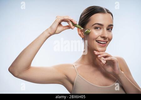 High-spirited lady with a jade roller looking forward Stock Photo