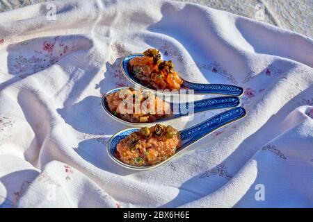 Specialty salmon meat with spices on the table. The meat is decoratively presented in ceramic spoons. Stock Photo