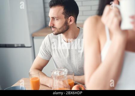 Unhappy tired man having breakfast at home with his wife Stock Photo