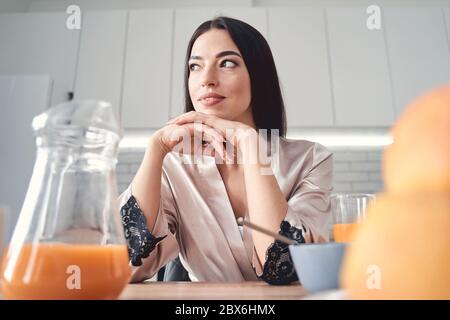 Thoughtful young woman having breakfast at home Stock Photo