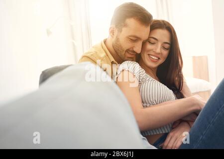Happy newlyweds holding each other by hands on a sofa Stock Photo