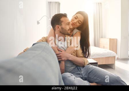 Adorable loving couple embracing on a soft couch at home Stock Photo