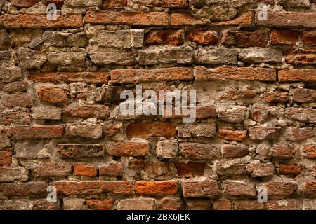 Ancient brick stone wall. Antique half-destroyed wall with brown handmade brickwork. Close up shot. Abstract texture or background Stock Photo