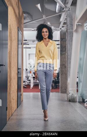 Slim dark-haired woman walking along the corridor Stock Photo