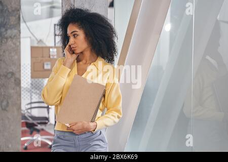 Despondent female office worker standing in the office corridor Stock Photo