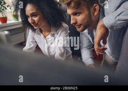 Curly-headed smiling woman and her pleased coworker Stock Photo