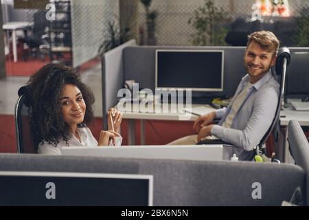 Two pleased young employees in their workplaces Stock Photo