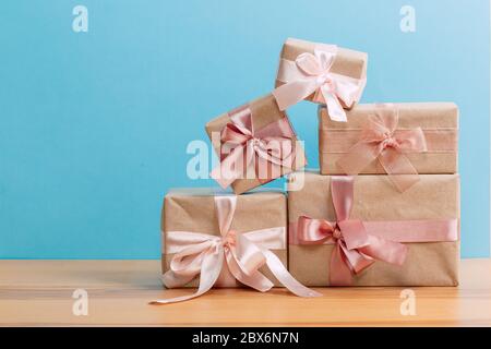 set of beautiful different gift boxes made by handmade with pink bows on a wooden table with a blue background Stock Photo