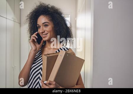 Cheerful curly-headed lady calling on the smartphone Stock Photo