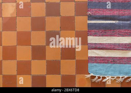 handmade carpet on an old retro tiled floor, carpet on the floor Stock Photo