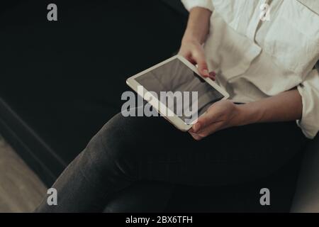 Mockup image of a woman sitting and holding white tablet pc with blank desktop screen Stock Photo