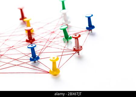 Network connection made from push pins and thread on blue background, close-up. Stock Photo