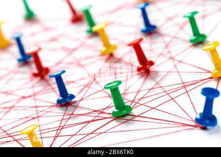 Network connection made from push pins and thread on blue background, close-up. Stock Photo
