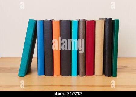Simple composition of many hardcover books, raw of books on a wooden table and a light background. I'm going back to school. Copy space Education. Stock Photo