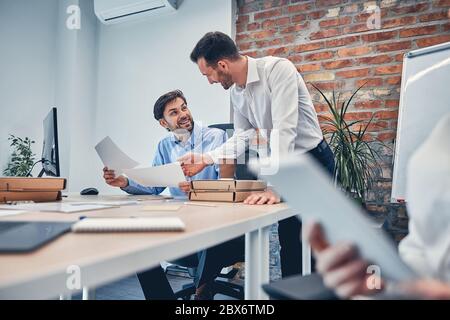 Young partners drawing up a contract in modern office Stock Photo