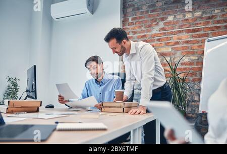 Two men in shirt holding documets and looking on it Stock Photo