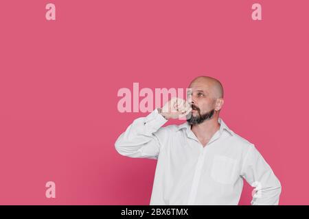 Handsome serious middle aged man meditate on pink background  Portrait of a senior man who thinks and holds a hand near his face leaning against a pin Stock Photo