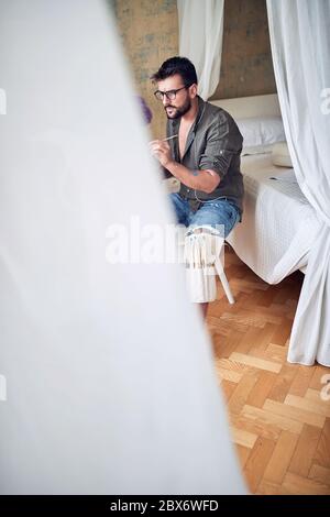 Young handsome male painter takes his work seriously despite relaxed atmosphere Stock Photo