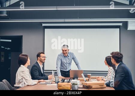 Smiling colleagues discussing new startup project with boss in office Stock Photo