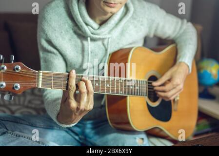 A young musician is learning to play the acoustic guitar. A man is playing a guitar close up Stock Photo