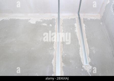 Aluminum profile for LED lighting placed in a wall with cement-lime plaster that goes into the ceiling in a newly built house. Stock Photo