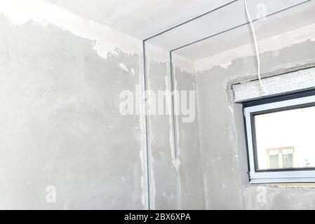 Aluminum profile for LED lighting placed in a wall with cement-lime plaster that goes into the ceiling in a newly built house. Stock Photo