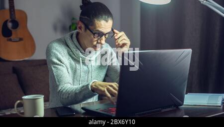 The man is working remotely using a laptop. Ability to work productively in home office mode for programmers, designers, and many other professionals Stock Photo