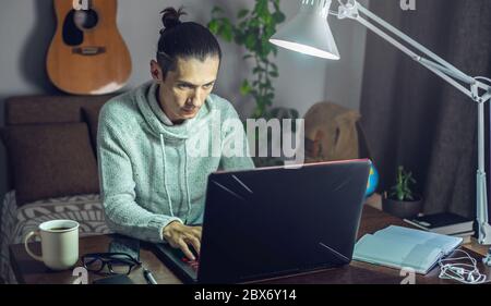 The man is working remotely using a laptop. A comfortable and convenient workplace at home for programmers, designers, and many other professionals Stock Photo