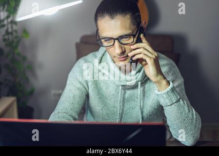 The man is working remotely using a laptop. Ability to work productively in home office mode for programmers, designers, and many other professionals Stock Photo