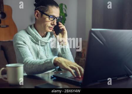 The man is working remotely using a laptop. Ability to work productively in home office mode for programmers, designers, and many other professionals Stock Photo