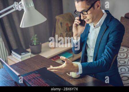 A male businessman is working remotely in home office mode. Online communication with employees and project management in a comfortable workplace Stock Photo