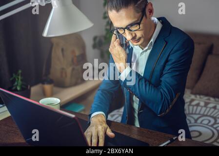 A male businessman is working remotely in home office mode. Online communication with employees and project management in a comfortable workplace Stock Photo