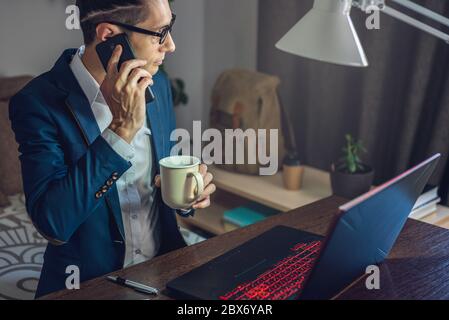 A male businessman is working remotely in home office mode. Online communication with employees and project management in a comfortable workplace Stock Photo