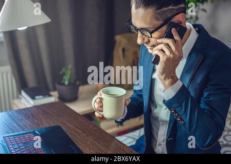 A male businessman is working remotely in home office mode. Online communication with employees and project management in a comfortable workplace Stock Photo