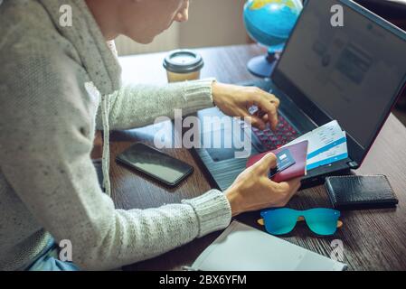 A man is buying air tickets over the Internet using a laptop for a long-awaited trip. Online purchase and booking of travel tours Stock Photo