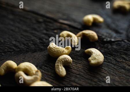 Cashew nuts scattered on the wooden vintage table. Cashew nut is a healthy vegetarian protein nutritious food. Stock Photo