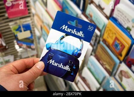 Montreal, Canada - May 03, 2020: Marshalls gift card in a hand over a stand with gift cards. Marshalls is a chain of American off-price department sto Stock Photo