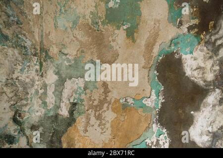 Brick wall. Old flaky white paint peeling off a grungy cracked wall. Cracks, scrapes, peeling old paint and plaster on background of old cement wall. Stock Photo