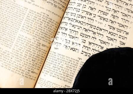 An open old Jewish book. Black jewish bale lies on an open scripture page. Hebrew text. Selective focus. Closeup Stock Photo