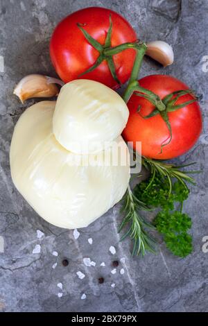 Food background with mozzarella, tomatoes, garlic cloves, herbs and spices.  Top view on slate. Stock Photo