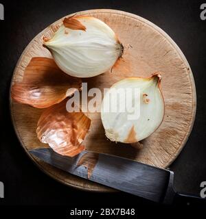 Cutting onions on round wooden vintage board.  Top view, on slate. Stock Photo