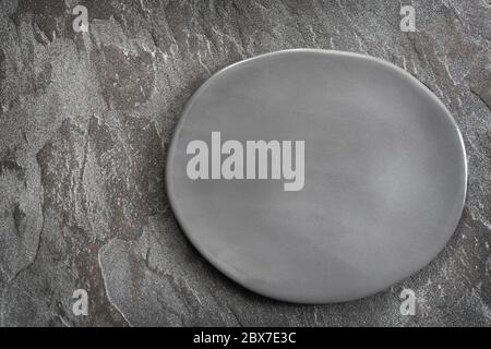 Empty rustic gray oval plate over slate, top view. Stock Photo
