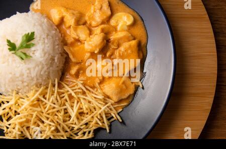 Chicken strogonoff with rice and french fries (potato sticks) on dish. Chicken stroganoff, is a dish originating from Russian cuisine that in Brazil i Stock Photo