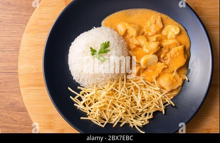 Chicken strogonoff with rice and french fries (potato sticks) on dish. Chicken stroganoff, is a dish originating from Russian cuisine that in Brazil i Stock Photo