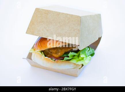 Large juicy burger in an open box made from sustainable cardboard isolated on white background. Stock Photo